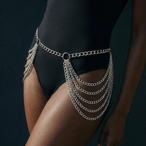 Silver chain body belt with layered draped fringe chains, worn on the hips over a black bodysuit for a bold statement look.