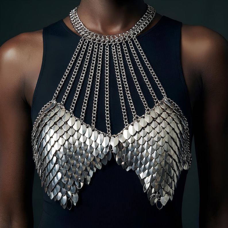 Silver metal scale bra with layered armor-style plates and chain halter straps, statement metallic festival body jewelry
