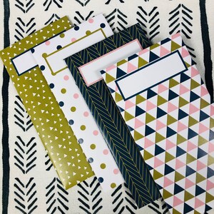 May include: Four different patterned paper envelopes with gold, pink, and navy blue geometric designs. Each envelope has a blank white label for writing.