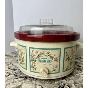 Puede incluir: Olla de cocción lenta Rival Crock-Pot color crema con tapa de cristal transparente y borde burdeos. La olla de cocción lenta presenta diseños florales y el texto "Rival Crock-Pot Slow Cooker/Server".