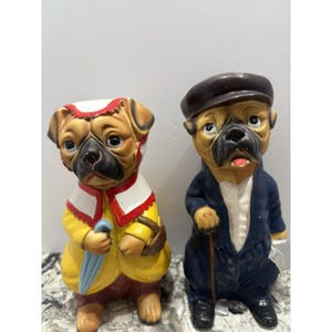 Może przedstawiać: Zestaw trzech ceramicznych kubków z nakrapianym, matowym wykończeniem. Kubki są w odcieniach kremu, jasnoszarym i ciemnoszarym. Każdy kubek ma prosty, minimalistyczny design, idealny do kawy lub herbaty.