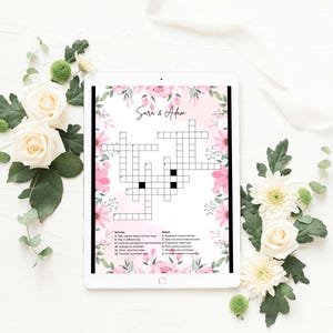 Può includere: Un tablet digitale che mostra un cruciverba intitolato Sara & Adam, decorato con un bordo floreale rosa. Il puzzle include indizi numerati per le voci orizzontali e verticali, su uno sfondo rosa tenue con fiori bianchi e rosa.