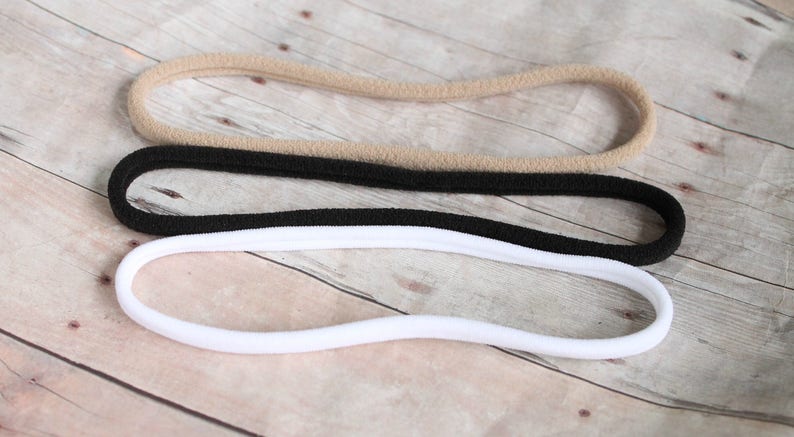 Pode incluir: Tr&ecirc;s el&aacute;sticos de cabelo em cores diferentes: bege, preto e branco. Os el&aacute;sticos de cabelo s&atilde;o feitos de um material macio e el&aacute;stico.