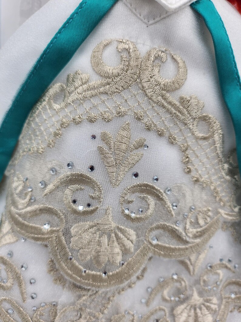 May include: White fabric with a gold embroidered design featuring a floral motif. The embroidery is accented with small, clear rhinestones.