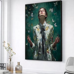 Può includere: Dipinto incorniciato raffigurante una persona con una giacca floreale con farfalle. La persona guarda verso l'alto con le braccia tese. Lo sfondo è verde scuro con farfalle bianche. La giacca ha motivi floreali gialli e bianchi.