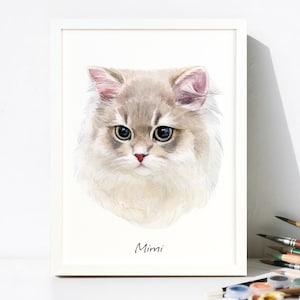 May include: A framed watercolor painting of a cat's face. The cat has light gray and white fur, green eyes, and a pink nose. The name "Mimi" is written in cursive below the cat's portrait.