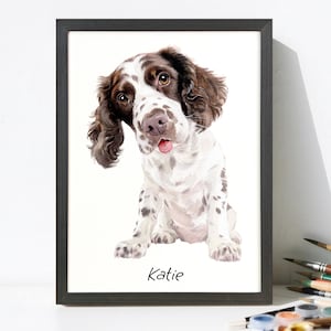May include: A framed watercolor painting of a Springer Spaniel dog. The dog has brown and white fur, with a pink tongue sticking out. The dog is sitting and looking at the viewer. The name "Katie" is written at the bottom.