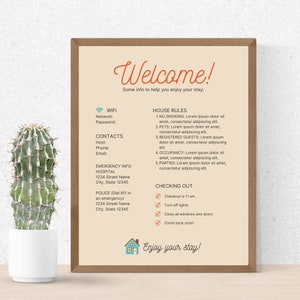 May include: A framed welcome sign with the text "Welcome!" in a decorative font. The sign includes house rules, contact information, and check-out instructions. A potted cactus is in the foreground.