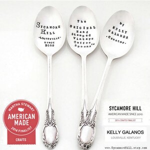 May include: Three silver vintage coffee spoons with hand-stamped text. The spoons are decorated with floral designs. The text on the spoons reads: "Sycamore Hill, Louisville, Since 2010", "The Original Hand Stamped Vintage Coffee Spoons", and "By Kelly Galanos, Creator."