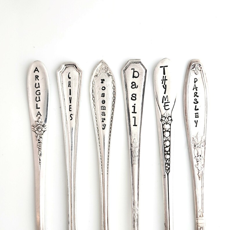 May include: Six silver spoons with engraved names of herbs: Arugula, Chives, Rosemary, Basil, Thyme, and Parsley.