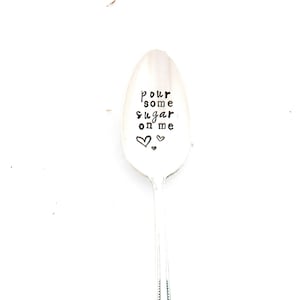 May include: A silver spoon with the words "Pour some sugar on me" engraved on the bowl. Two small hearts are engraved below the text.