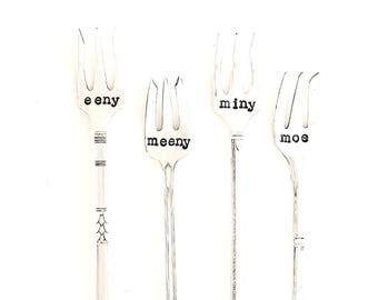 May include: Four silver forks with the words "eeny", "meeny", "miny", and "moe" engraved on them.