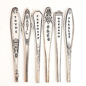 May include: Six silver spoons with black lettering, each labeled with a different herb: Thyme, Basil, Rosemary, Sage, Oregano, and Parsley.