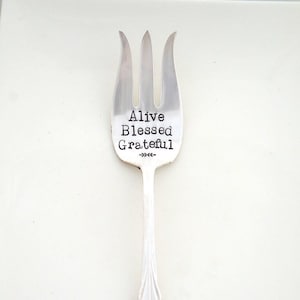 May include: A silver fork with the words "Alive Blessed Grateful" engraved on the front.