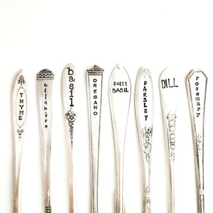 May include: Nine silver spoons with engraved labels for different herbs, including thyme, cilantro, basil, oregano, sweet basil, parsley, dill, and rosemary.
