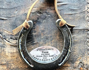 May include: A silver horseshoe with a leather strap for hanging. The horseshoe has a metal plaque with the text "Jeff & Lori's Barn Est. 2025 Bless this barn with love & happiness".
