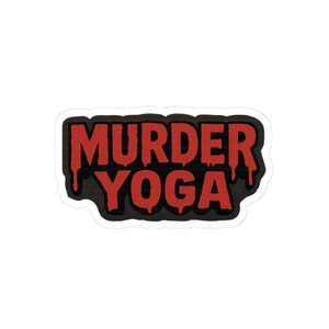 May include: A sticker featuring the text "MURDER YOGA" in red, dripping-style lettering, set against a black backdrop. The sticker has a white border. The design is striking and likely made of a durable material like vinyl.