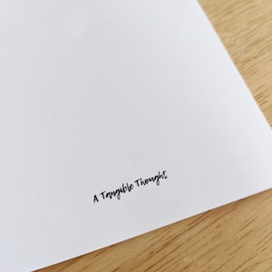 May include: A white card with the text "A Tangible Thought" printed in black ink.