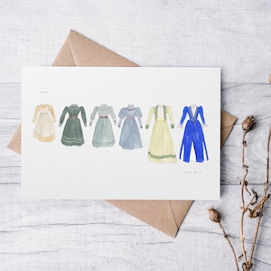 May include: Watercolour illustration of six vintage dresses in cream, green, blue, and yellow. The dresses are on a white card with text at the top and bottom. The card rests on a wooden surface. The card is in an envelope.