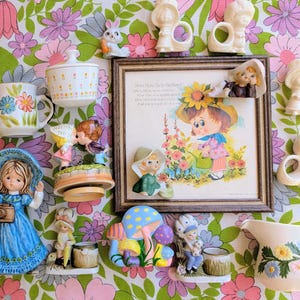 May include: A collection of vintage ceramic figurines and a framed print featuring a child in a garden with the text Mary, Mary, Quite Contrary. The set includes a blue-dressed girl, a mushroom-shaped piece, a pitcher, and various small decorative items.