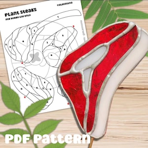 May include: A stained glass steak in red and white, mounted on a wooden stick. A PDF pattern for hobby use is in the background, with the text "Plant Steaks" and "PDF Pattern".