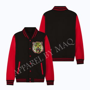 Puede incluir: Chaqueta de béisbol negra y roja con un rostro de tigre bordado en el pecho izquierdo. La chaqueta tiene cierre de cremallera y puños y cintura de canalé.
