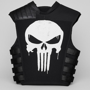 May include: Black vest with a white skull graphic. The vest has black straps on the sides and padded shoulder accents. The skull design has a distressed, dripping effect, adding a unique visual element.