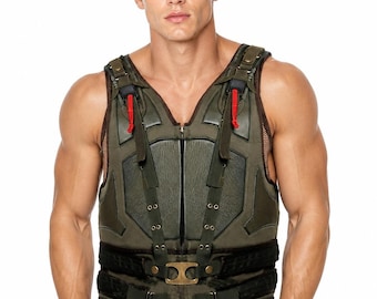 May include: An olive green tactical vest featuring a structured front panel with dark green accents, a central zip closure, and adjustable straps with brass-toned metal buckles. The vest includes red pull tabs on the shoulders and black mesh side panels.