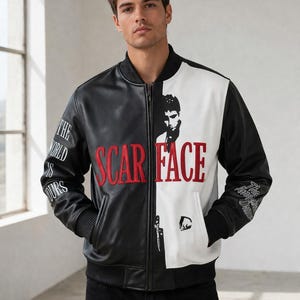 May include: Black and white leather jacket with the text "SCAR FACE" in red. The jacket features a portrait and text on the sleeves. The jacket has a black ribbed collar, cuffs, and hem.