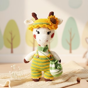 May include: A crocheted giraffe doll, wearing a yellow hat with a sunflower, green and yellow striped dungarees, and a matching green bag. The giraffe has brown horns, white ears, and red cheeks. The doll is on a cream-coloured blanket.