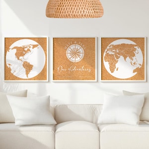 May include: Three framed corkboard art pieces. Two feature white world maps, and the center one has a compass design with the text "Matt & Tara" and "Our Adventures" in white. The frames are white, and the background is a natural cork color.