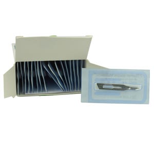 Può includere: Una scatola di lame chirurgiche sterili, con singole lame in confezioni protettive. Le lame sono di colore argento e hanno una punta affilata. La scatola è bianca e aperta, rivelando le lame all'interno. La confezione è blu e bianca.