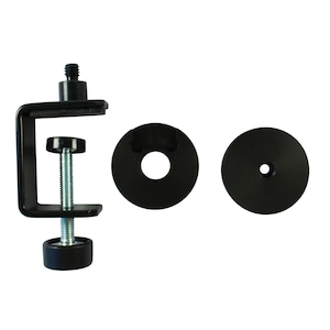 Puede incluir: Una abrazadera en C de metal negro con un tornillo roscado y una base redonda. También se incluyen dos arandelas circulares negras. La abrazadera está diseñada para fijarse a una superficie y sujetar un objeto en su lugar.