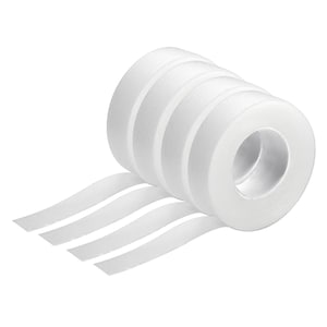 May include: Several rolls of white adhesive tape, with strips of tape unravelling from the rolls. The tape is a solid white colour and appears to be made of a flexible material.