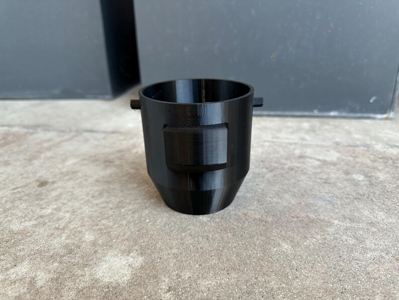 May include: A black plastic 3D printed funnel with a rectangular opening on the side.