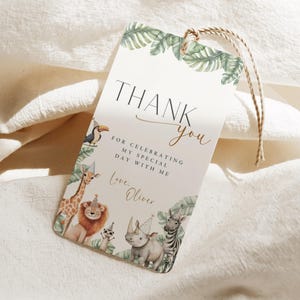 May include: A rectangular thank you tag with a jungle animal theme. The tag features a toucan, giraffe, lion, rhino, and zebra. The text reads "Thank you" and "For celebrating my special day with me."