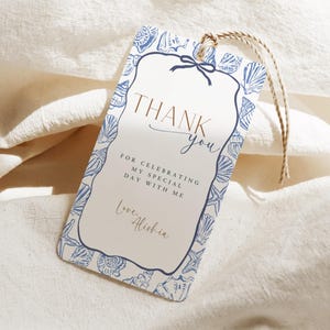 May include: A white gift tag with a blue seashell border and the words "Thank You" in elegant script. The tag includes the message "For celebrating my special day with me" and is tied with a natural twine.