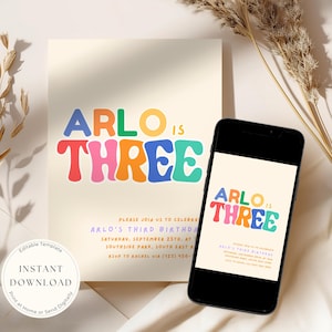 May include: A birthday invitation template featuring the text ARLO IS THREE in colourful, wavy, retro-style typography on a cream background. The invitation includes event details and is displayed on a physical card and a black smartphone screen.