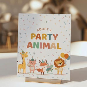 May include: A party-themed sign with the text "ADOPT A PARTY ANIMAL" in colorful letters. The sign features illustrations of a giraffe, cat, fox, and lion, all wearing party hats and holding party favors. The sign is held by a gold metal stand.