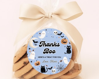 May include: A clear cellophane bag tied with a beige bow, filled with cookies. A round sticker on the bag reads "Thanks Boo" with Halloween-themed illustrations of ghosts, bats, pumpkins, and a black cat. Text below says "Here's a treat for you, Love, Oliver."