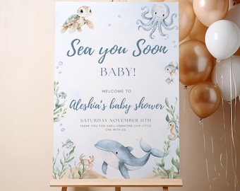 May include: A baby shower sign on an easel with watercolor illustrations of sea creatures. The sign reads "Sea you Soon BABY!" and welcomes guests to Aleshia's baby shower on November 11th.