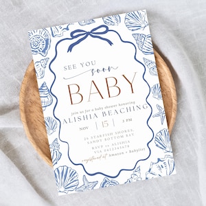 May include: Baby shower invitation with a seashell theme. The invitation features blue seashell illustrations around the border and a blue bow at the top. The text reads "See you soon BABY" and includes event details.