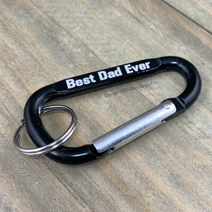 May include: Black carabiner keychain with a silver ring and the text "Best Dad Ever" printed in white.