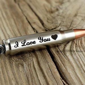 May include: A silver bullet keychain with a key ring and the words "I Love You" engraved on the side. The bullet has a copper tip.