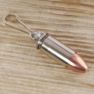 May include: A silver bullet keychain with a copper tip and a silver clip.