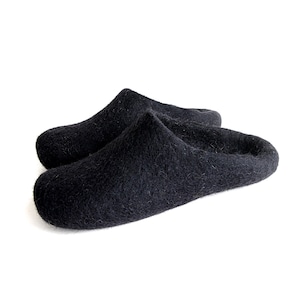 May include: A pair of black wool slippers. The slippers are made of a soft, fuzzy material and have a rounded toe.