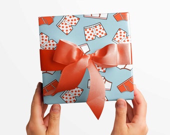 May include: A blue gift box with a red bow. The box is wrapped in paper with a pattern of red and white underwear.