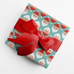 Christmas gift wrapped in modern, geometric Santa wrapping paper with red ribbon by Gigglemugg