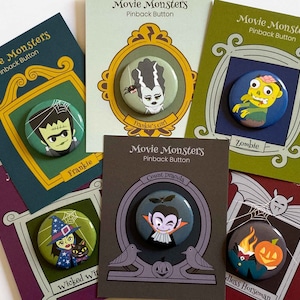 Puede incluir: Nueve botones de solapa coloridos con varios monstruos de películas. Los botones se muestran en cartulina colorida con un marco decorativo y el texto "Movie Monsters" y "Pinback Button". Los personajes incluyen Frankie, Frankie's Girl, Zombie, Wicked Witch, Count Dracula y Headless Horseman.