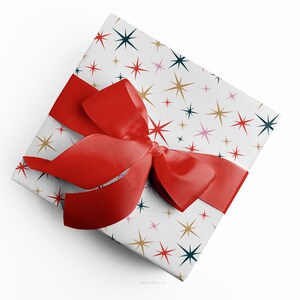 Christmas gift wrapped in mid-century modern, Christmas stars wrapping paper with a red ribbon designed by Marisa Dolan